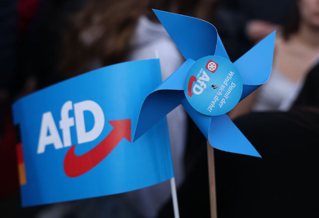 La gente sostiene una bandera de AfD y una hélice giratoria en una manifestación de la extrema derecha Alternativa para Alemania (AfD) antes de las elecciones alemanas el 22 de febrero de 2025 en Erfurt, Alemania.