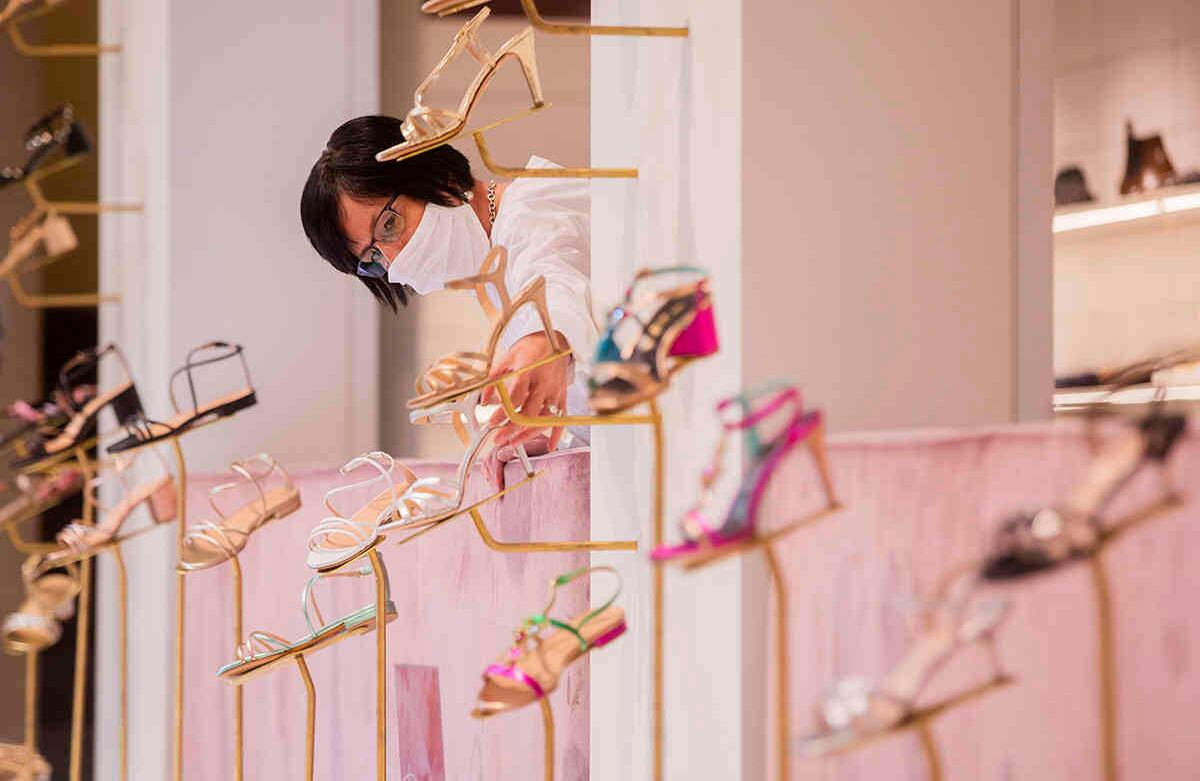 Una vendedora con protección bucal y nasal contra el coronavirus decora el escaparate de una zapatería en Münster, Alemania. Rolf Vennenbernd-A través de AP