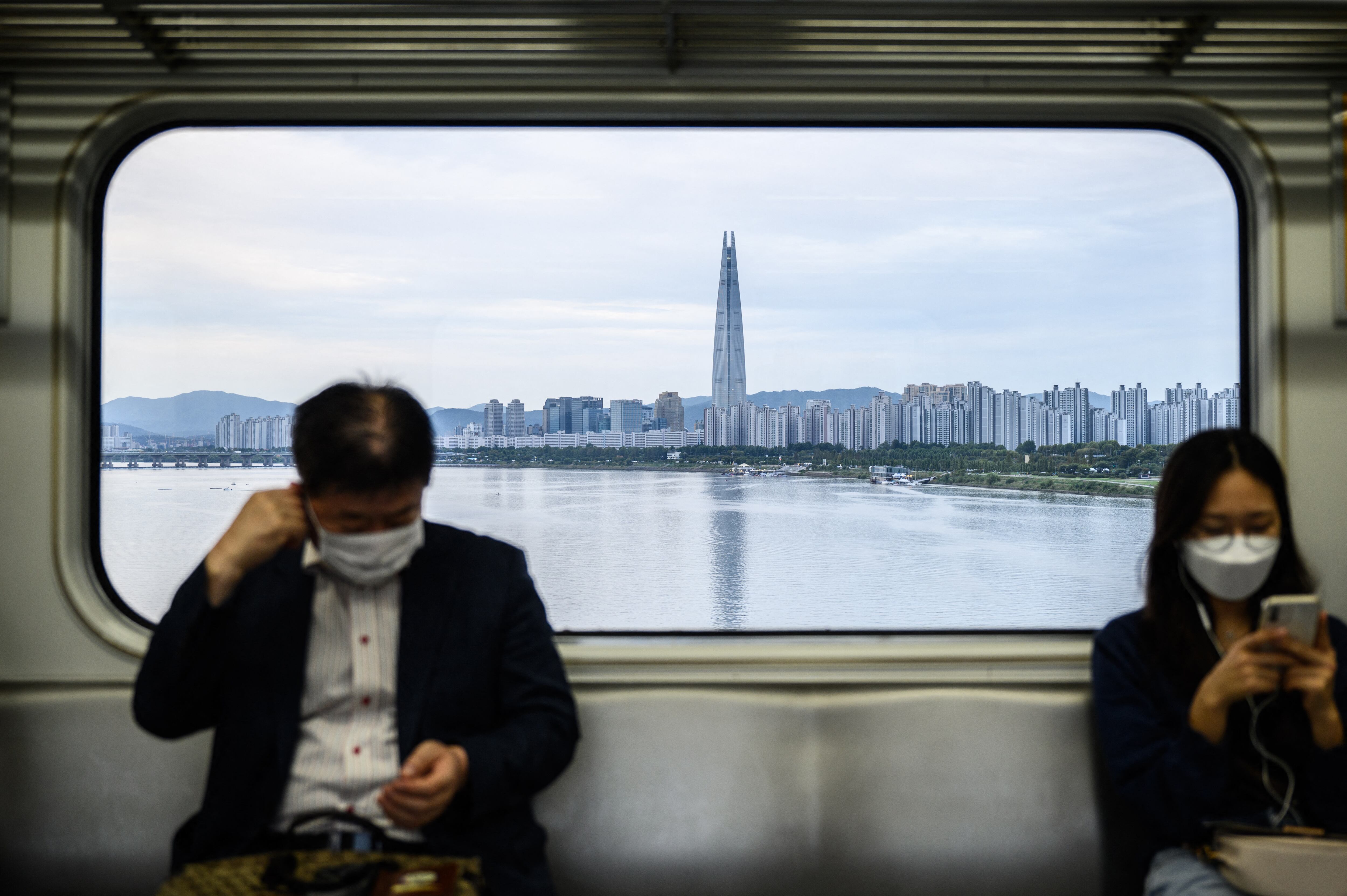 Un tren del metro cruza un puente con vistas al río Han y al rascacielos Lotte World Tower de 123 pisos en Seúl.