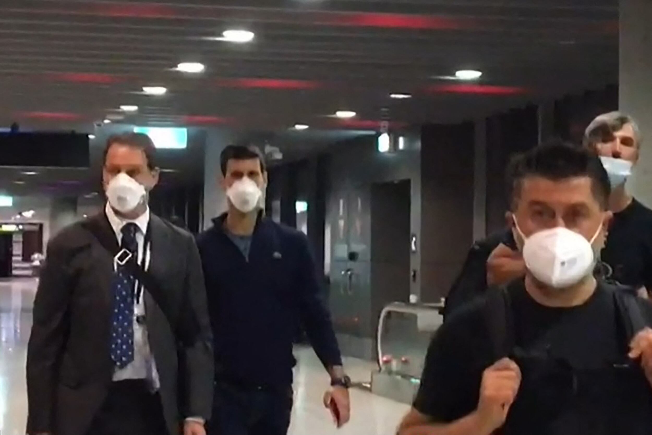 Novak Djokovic (2do L) preparándose para partir del aeropuerto de Melbourne en Melbourne el 16 de enero de 2022, después de perder una batalla legal sensacional sobre su estado de vacunación contra el coronavirus con su sueño de lograr un Grand Slam número 21 récord hecho trizas.