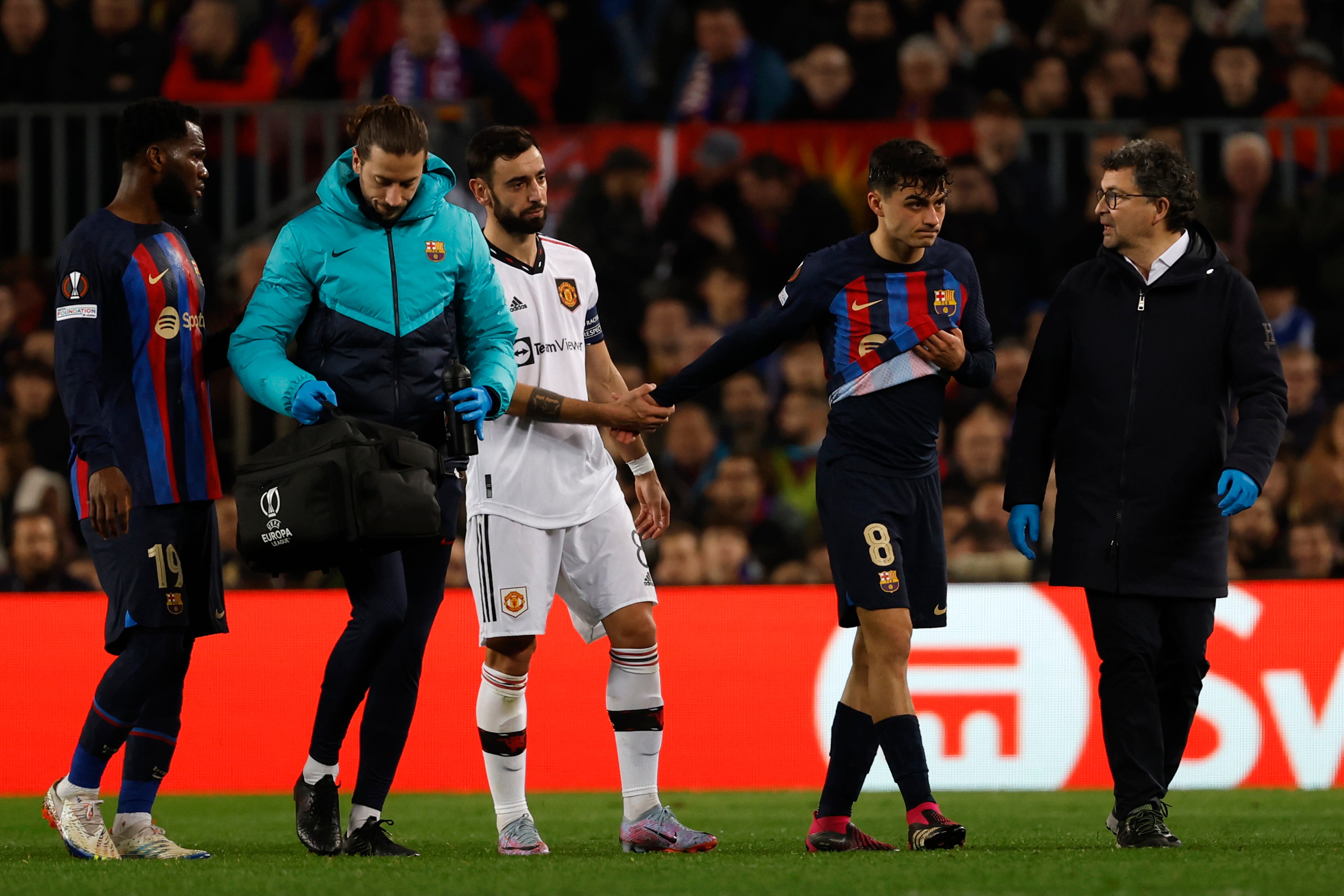 Manchester United's Bruno Fernandes, center, comforts Barcelona's Pedri, second right, as he walks off the pitch while he is substituted by Barcelona's Sergi Roberto after being injured during the Europa League playoff first leg soccer match between Barcelona and Manchester United at the Camp Nou stadium in Barcelona, Spain, Thursday, Feb. 16, 2023. (AP Photo/Joan Monfort)