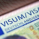 Visa stamp in passport close-up. German visitor visa at border control. Macro view of Schengen visa for tourism and travel in EU. Document for multiple entry. Legal immigration to Germany and Europe.