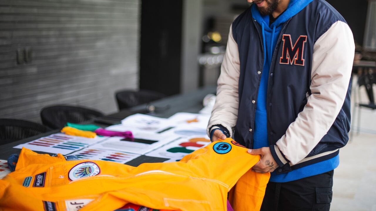 Maluma verificando una de las prendas de una colección de modas.