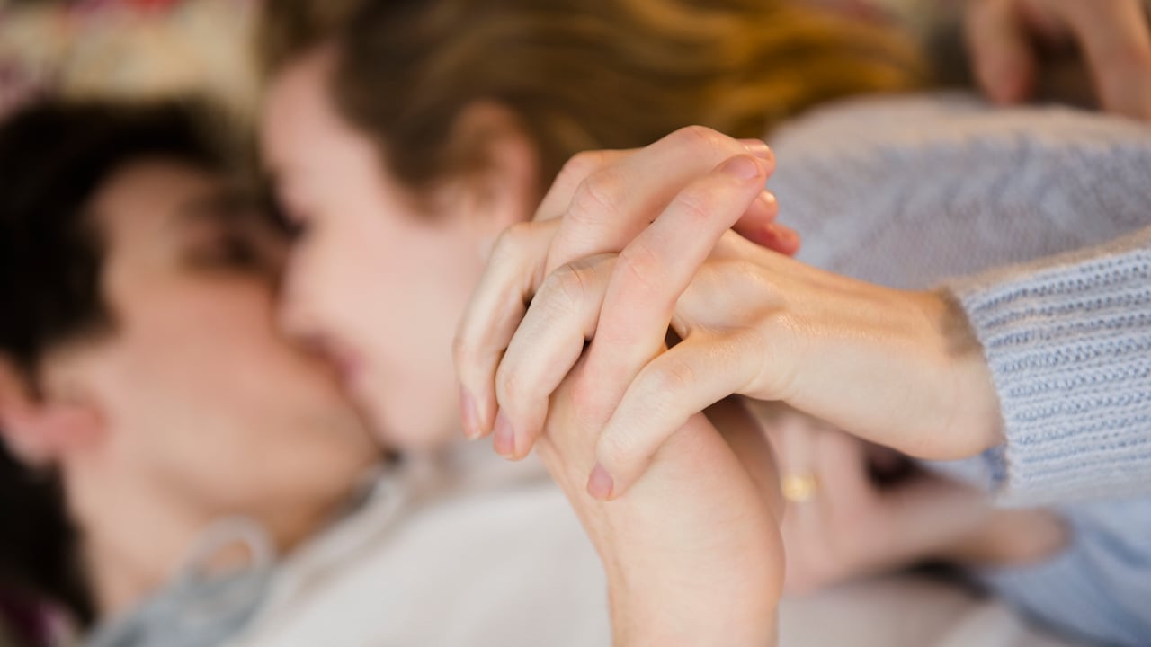Couple holding hands while kissing