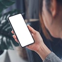 Smartphone mockup. Women hand using mobile phone on sofa at home office. White screen empty space for design concept.