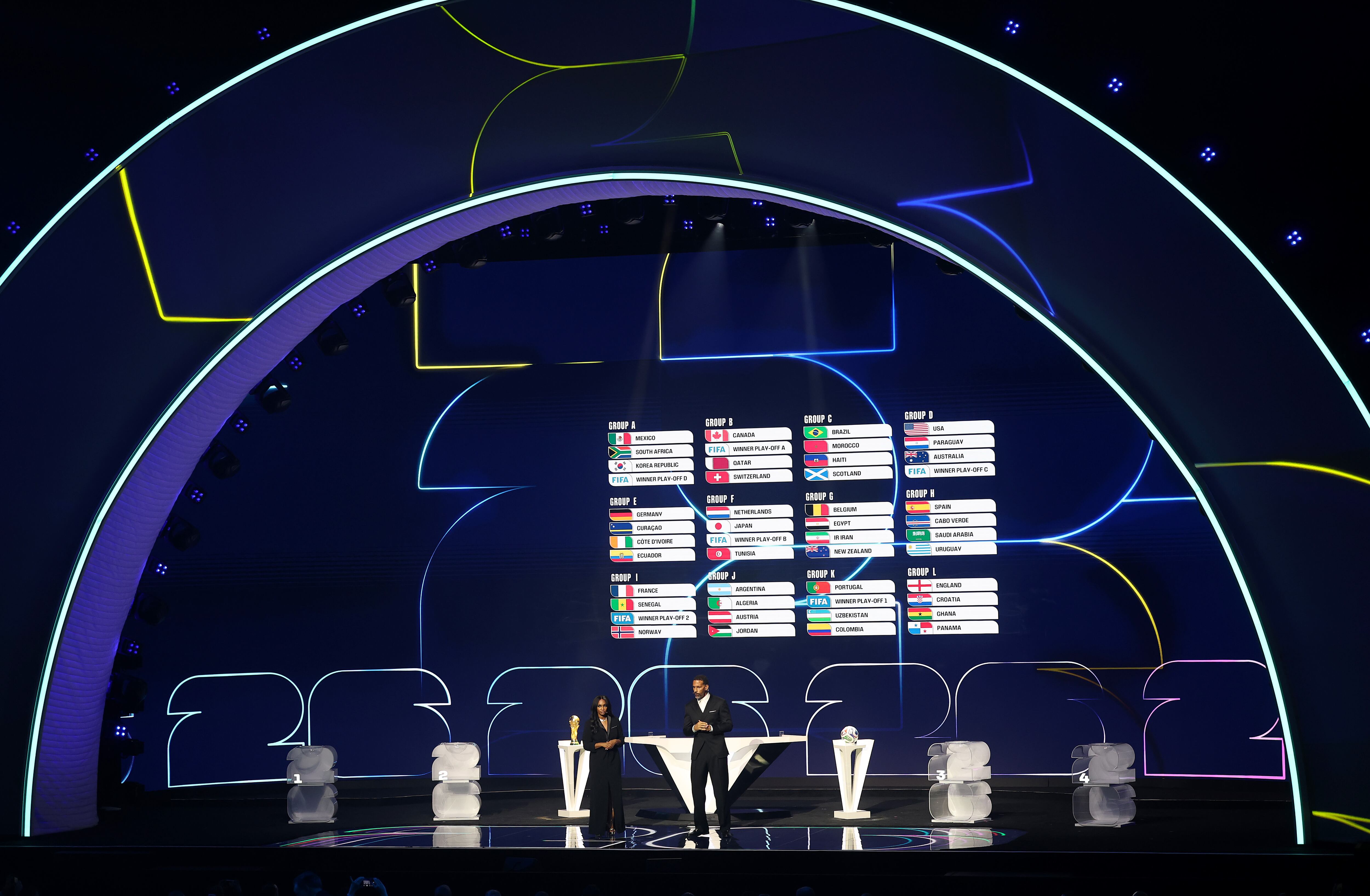 La leyenda de la FIFA Rio Ferdinand y la codirectora Samantha Johnson hablan mientras la pantalla muestra el sorteo final durante el sorteo oficial de la Copa Mundial de la FIFA 2026 en el Centro John F. Kennedy.