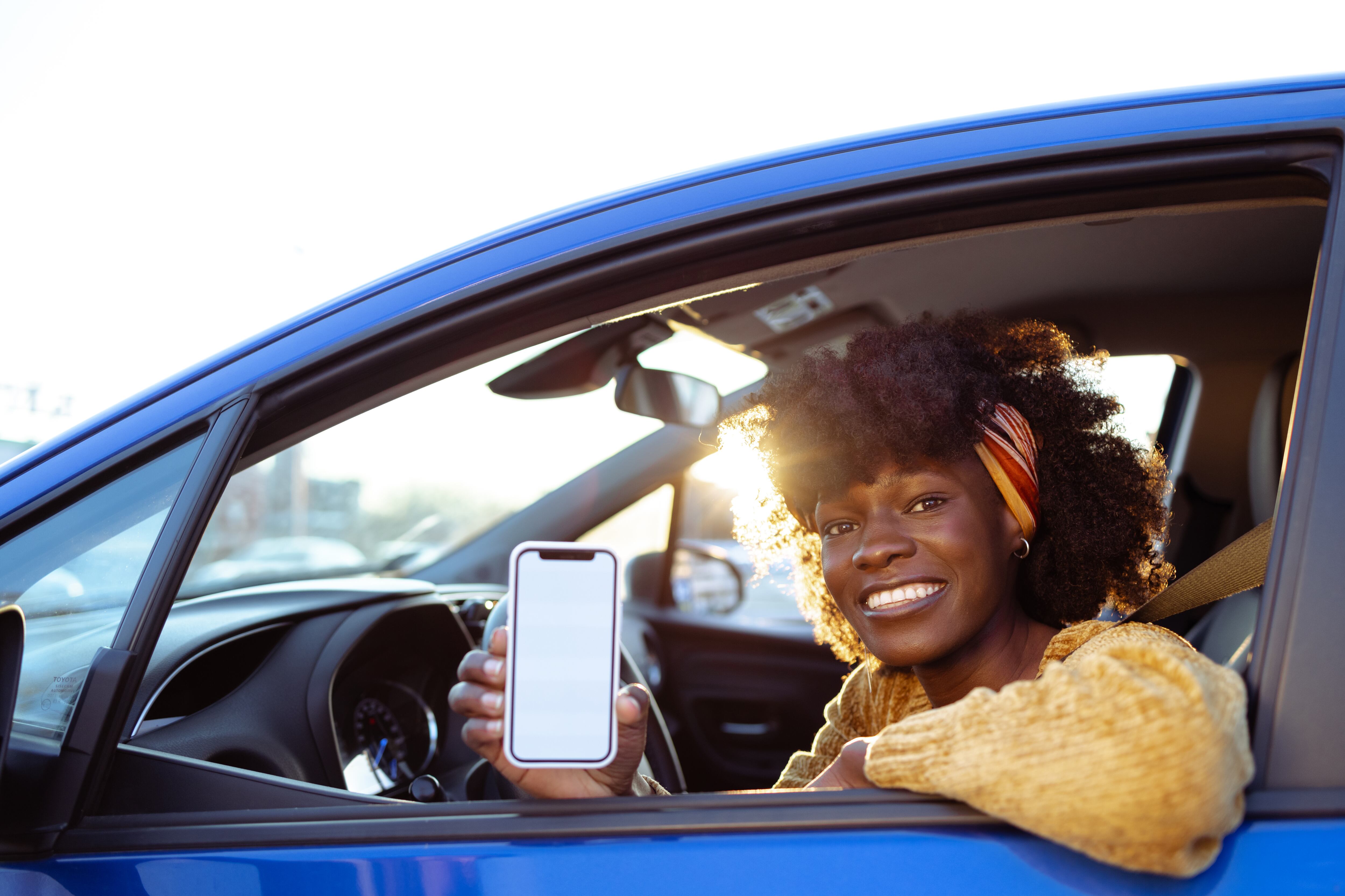Está sentada en el asiento del conductor del coche.