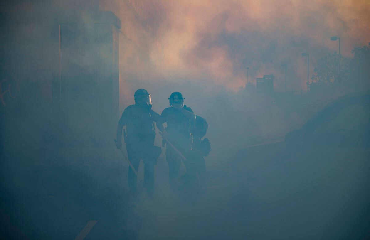 Oficiales de policía caminan a través de una nube de gas lacrimógeno, el jueves 28 de mayo de 2020, en St. Paul, Minnesota. (Foto AP / John Minchillo)