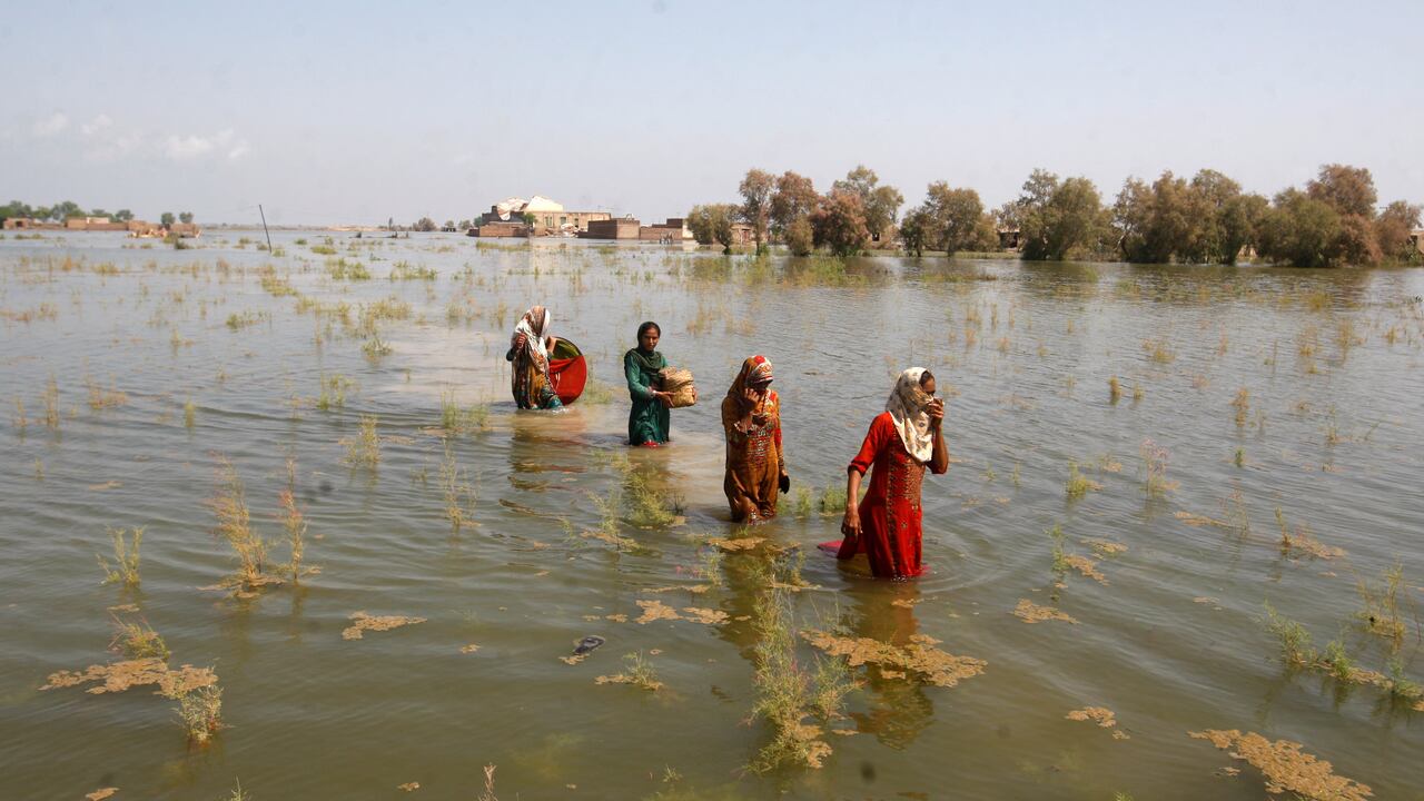 Mujeres paquistaníes caminan a través de las aguas de la inundación mientras se refugian en el distrito de Shikarpur de la provincia de Sindh, en Pakistán, el viernes 2 de septiembre de 2022. (AP Photo/Fareed Khan).