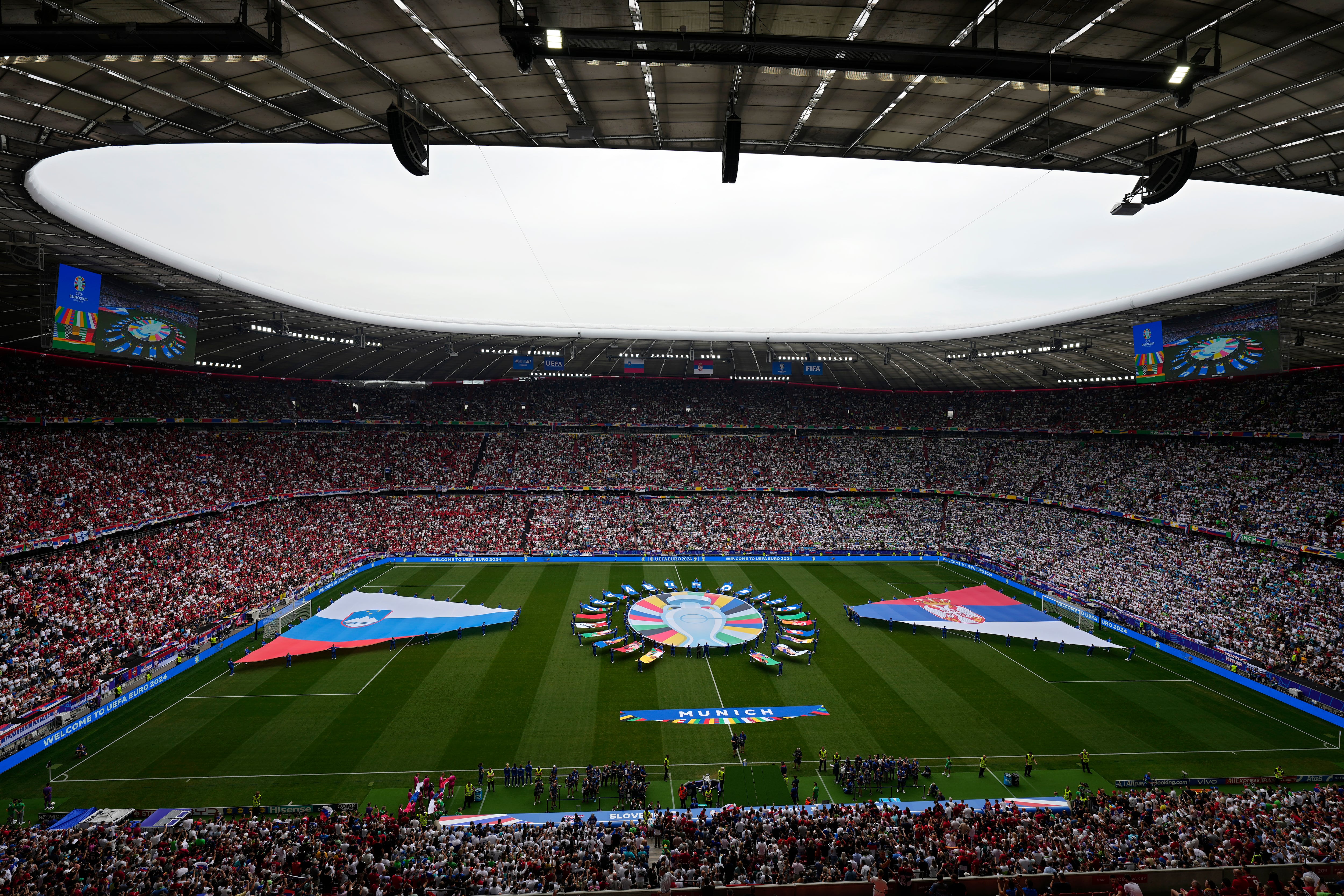 Volunteers display banners on the pitch before a Group C match between Slovenia and Serbia at the Euro 2024 soccer tournament in Munich, Germany, Thursday, June 20, 2024. (AP Photo/Ariel Schalit)