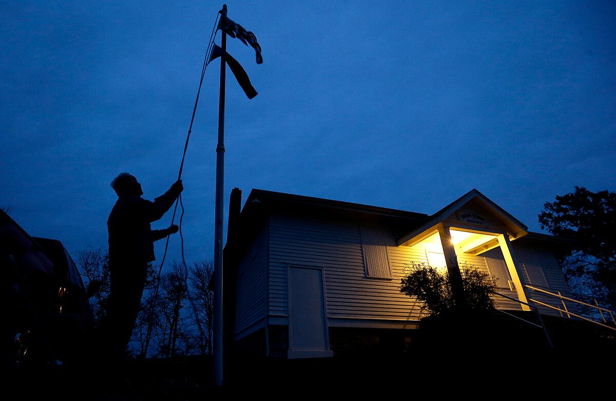 Bob Wootten iza una bandera a las afueras de la escuela Brown en Kansas, Estados Unidos, donde se preparan para abrir las urnas para las elecciones legislativas de este martes. (AP)