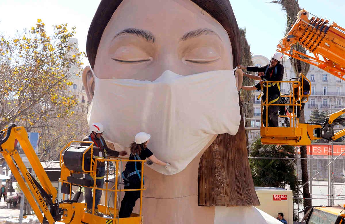 Trabajadores colocan una máscara sobre una figura de las Fallas en Valencia. La imagen es del miércoles pasado. El festival de las Fallas, que debía tener lugar este viernes, fue cancelado por el brote de coronavirus. Alrededor del mundo, una gran cantidad de festividades y espectáculos han sido cancelados por precaución. Foto: Alberto Saiz/ AP 