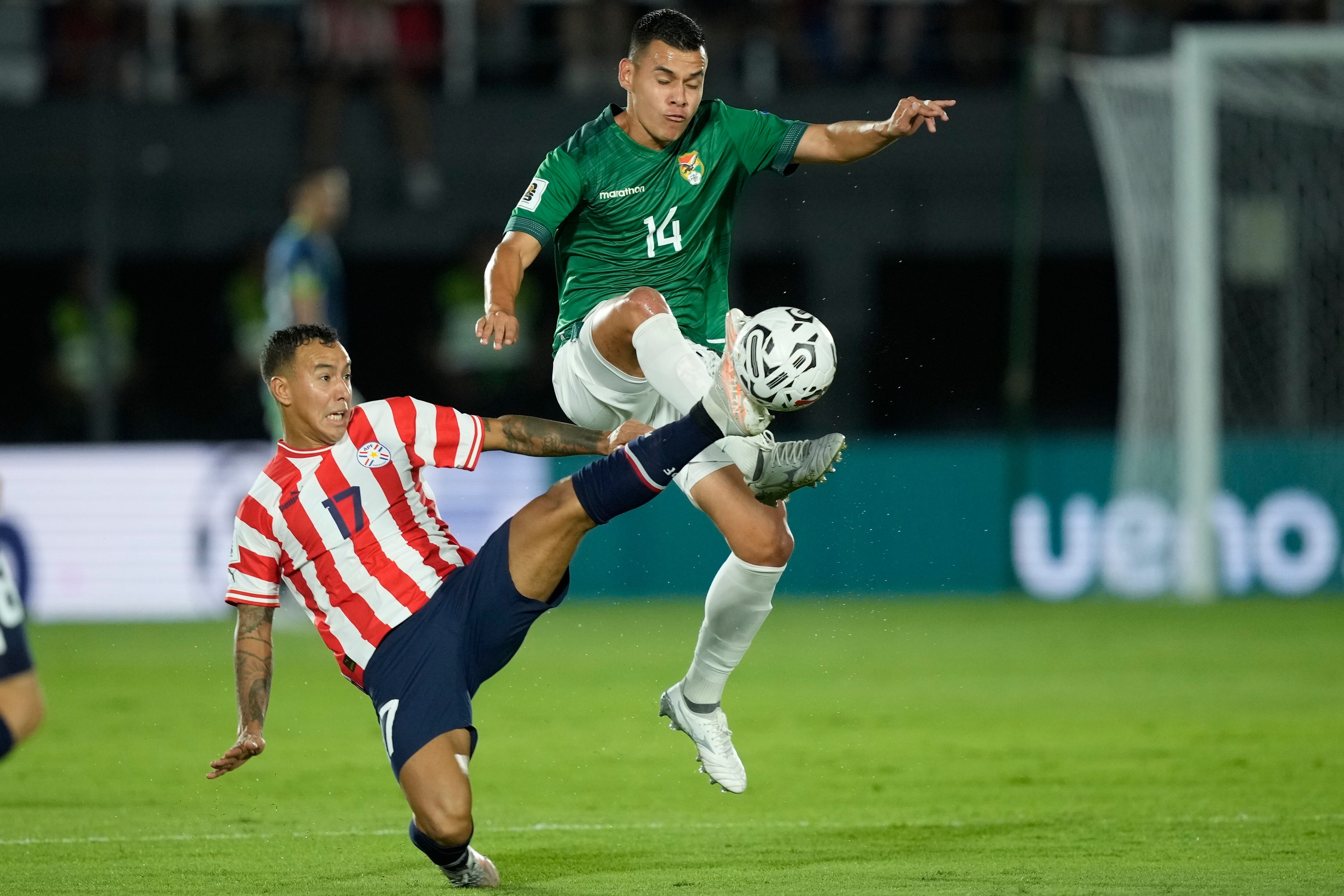 Moisés Villarroel de Bolivia, derecha, pelea por el balón con Alejandro Romero de Paraguay durante un partido de fútbol de clasificación para la Copa Mundial de la FIFA 2026, en el Estadio Defensores del Chaco en Asunción, Paraguay, el martes 17 de octubre de 2023. (Foto AP/Jorge Saenz )