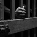 Human hands with sand on them on cage bars