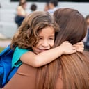 Latin American boy greeting his mother with a hug while she is picking him up from school - lifestyle concepts