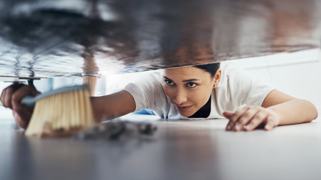 Mujer barriendo debajo de la cama
