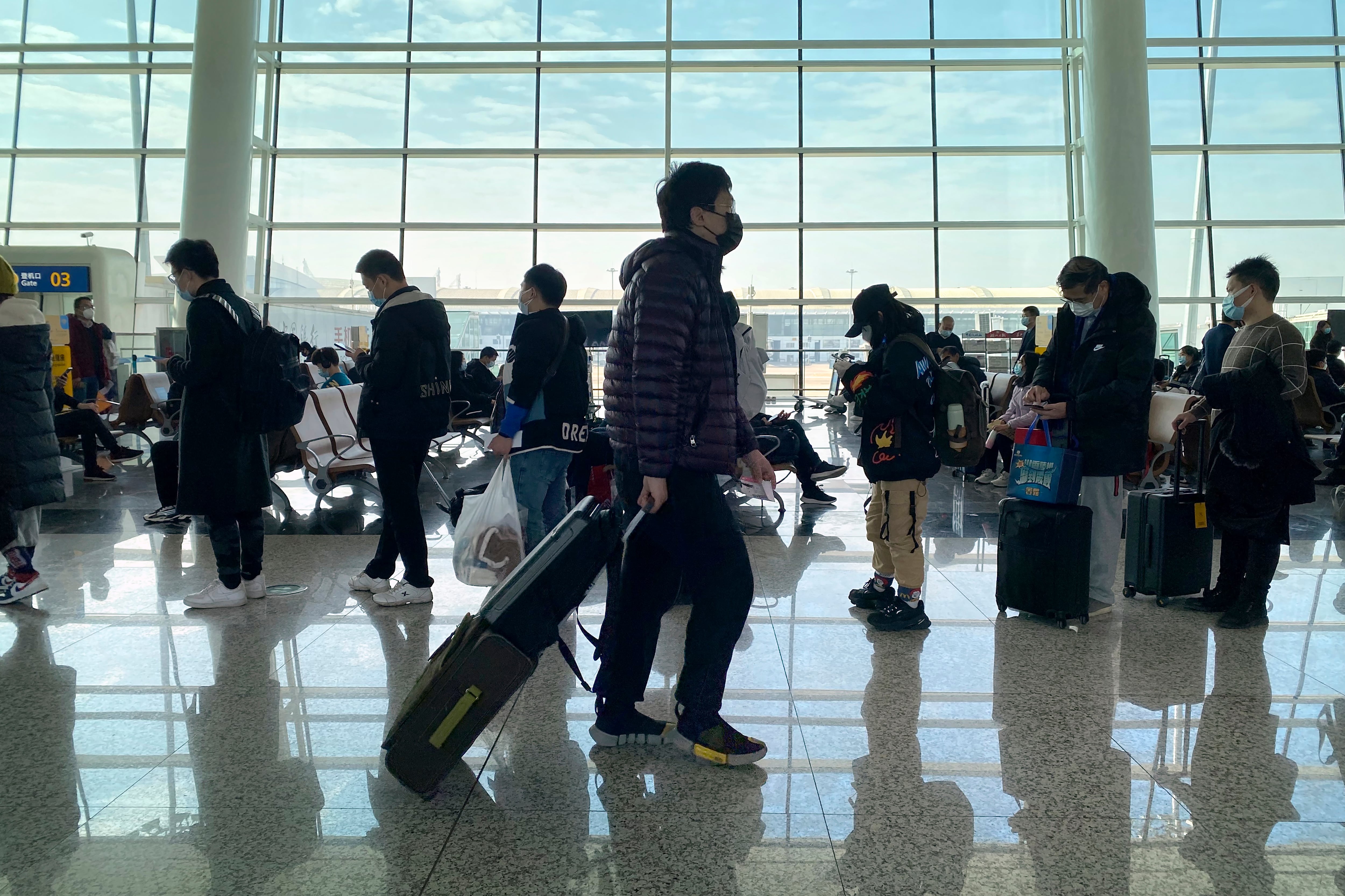Passengers wearing face masks to protect against the spread of the coronavirus line up at a boarding gate at Wuhan Tianhe International Airport in Wuhan in central China's Hubei Province, Thursday, Jan. 14, 2021. China is seeing a new surge in coronavirus cases in its frozen northeast as a World Health Organization team was due to arrive to probe the origins of the pandemic. (AP Photo/Ng Han Guan)