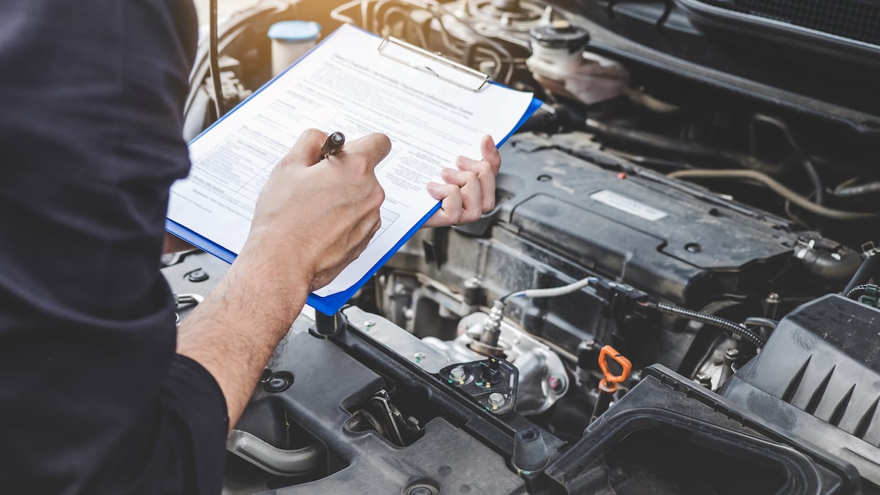 Services car engine machine concept, Automobile mechanic repairman checking a car engine with inspecting writing to the clipboard the checklist for repair machine, car service and maintenance.
