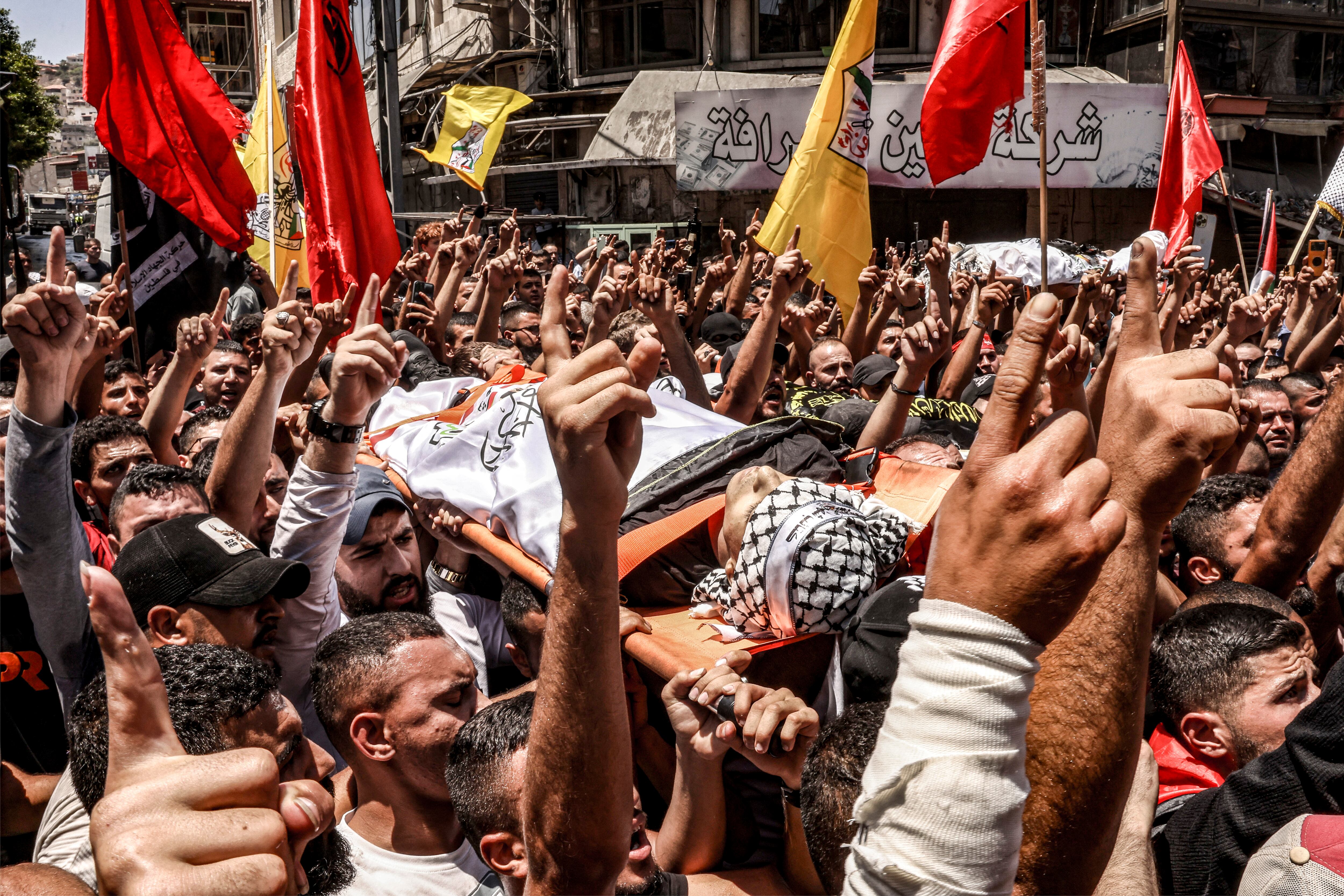 Los dolientes gesticulan y cantan eslóganes mientras marchan con los cuerpos de los palestinos muertos en los enfrentamientos del día anterior en la operación militar israelí durante el funeral en Jenin, en la Cisjordania ocupada