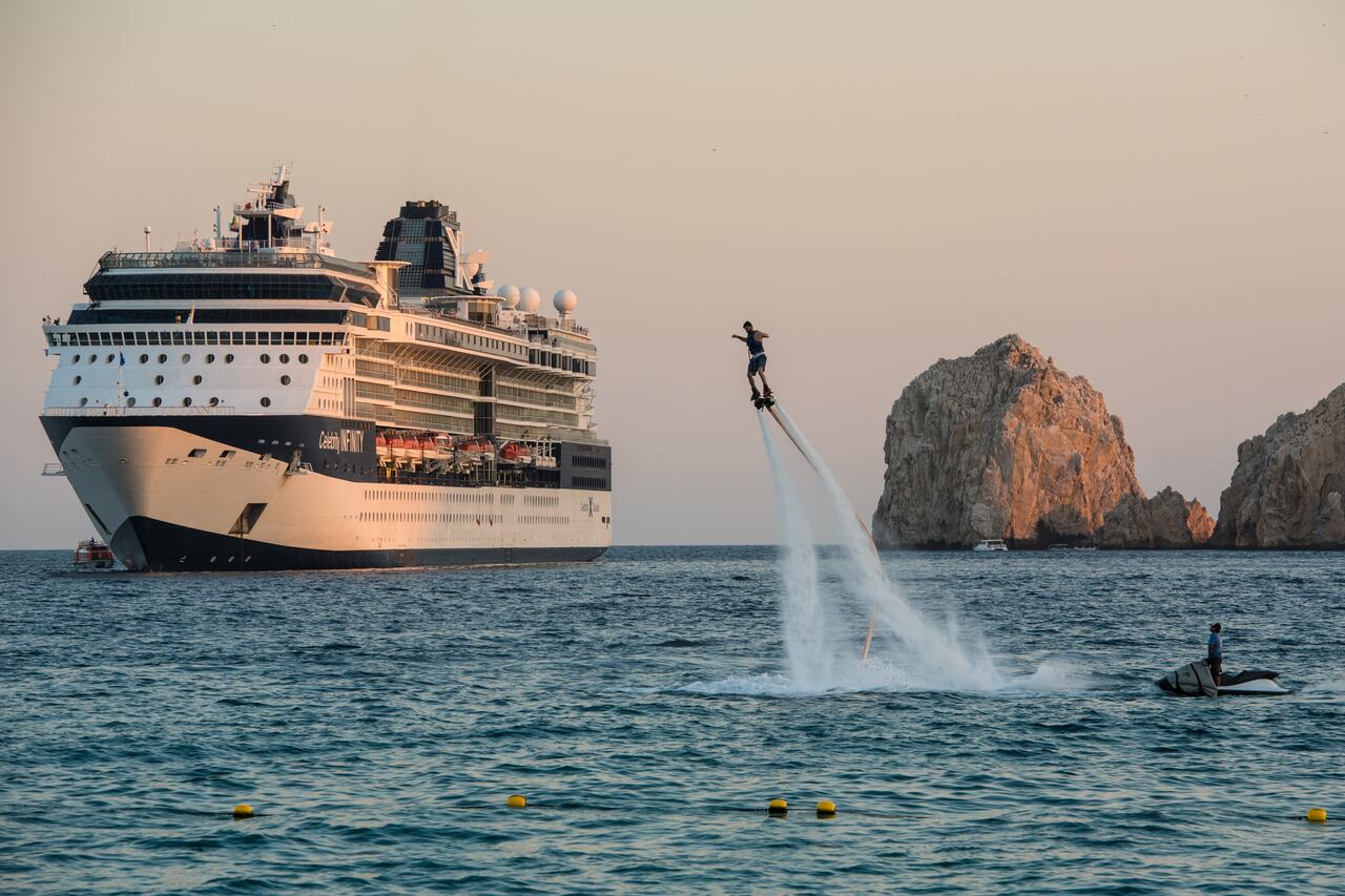 Un piloto de flyboard se eleva por el aire en Cabo San Lucas frente a un crucero anclado.