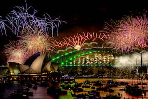 Fireworks explode over the Sydney Harbour Bridge and Sydney Opera House (L) during New Year's Eve celebrations in Sydney on January 1, 2024. (Photo by Izhar KHAN / AFP)