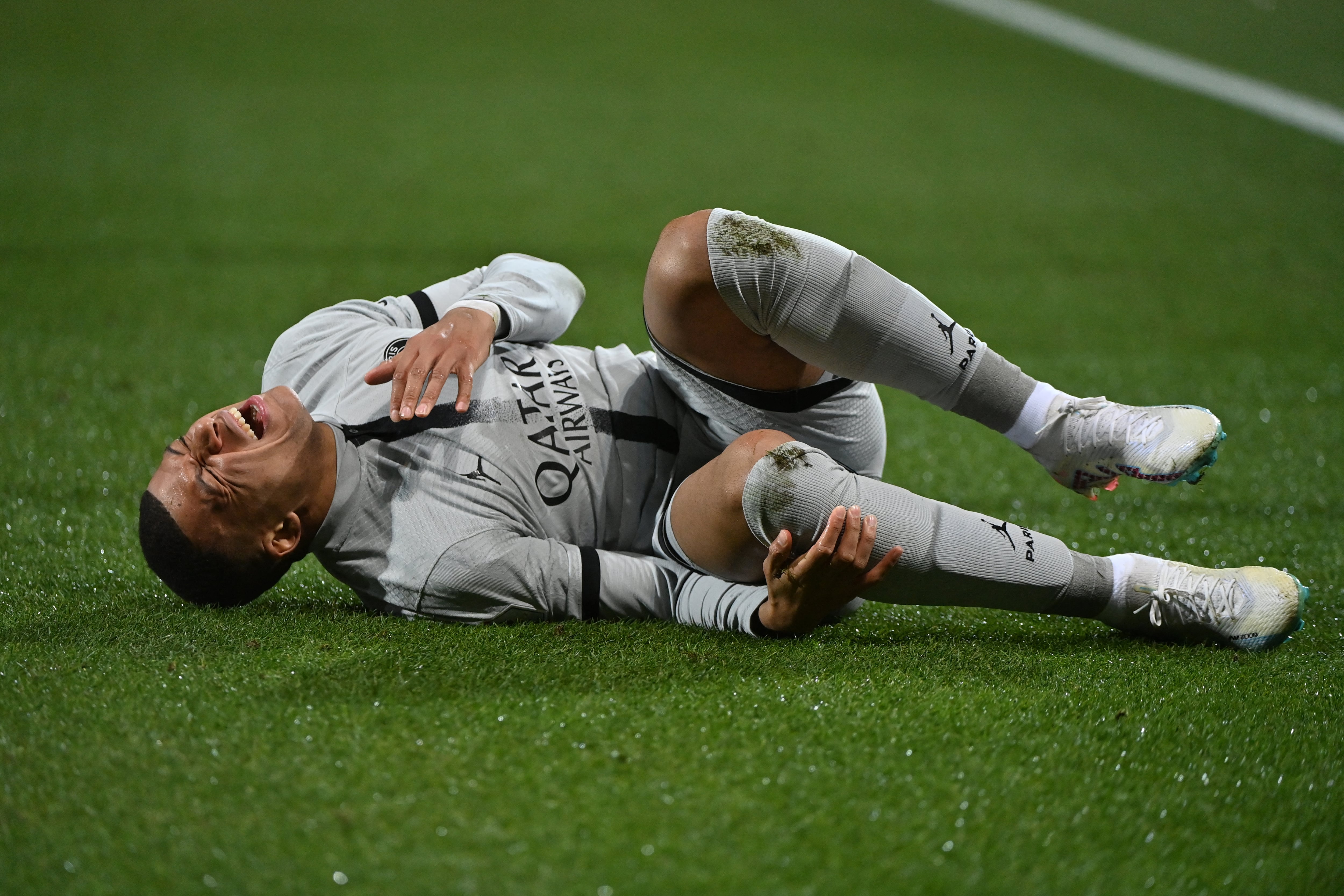 Paris Saint-Germain's French forward Kylian Mbappe lies on the ground after getting injured during the French L1 football match between Montpellier Herault SC and Paris Saint-Germain (PSG) at Stade de la Mosson in Montpellier, southern France on February 1, 2023. (Photo by Sylvain THOMAS / AFP)