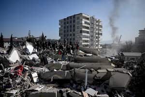 La gente espera mientras los rescatistas realizan operaciones de búsqueda entre los escombros de los edificios derrumbados en Kahramanmaras, el 9 de febrero de 2023. (Foto de OZAN KOSE / AFP)
