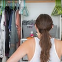 Esta es una joven adulta con las manos en las caderas tratando de decidir qué ponerse de su armario bien organizado.