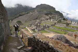 Un trabajador de mantenimiento lleva una bolsa de piedras en el sitio arqueológico de Machu. Foto: AP / Martin Mejía.