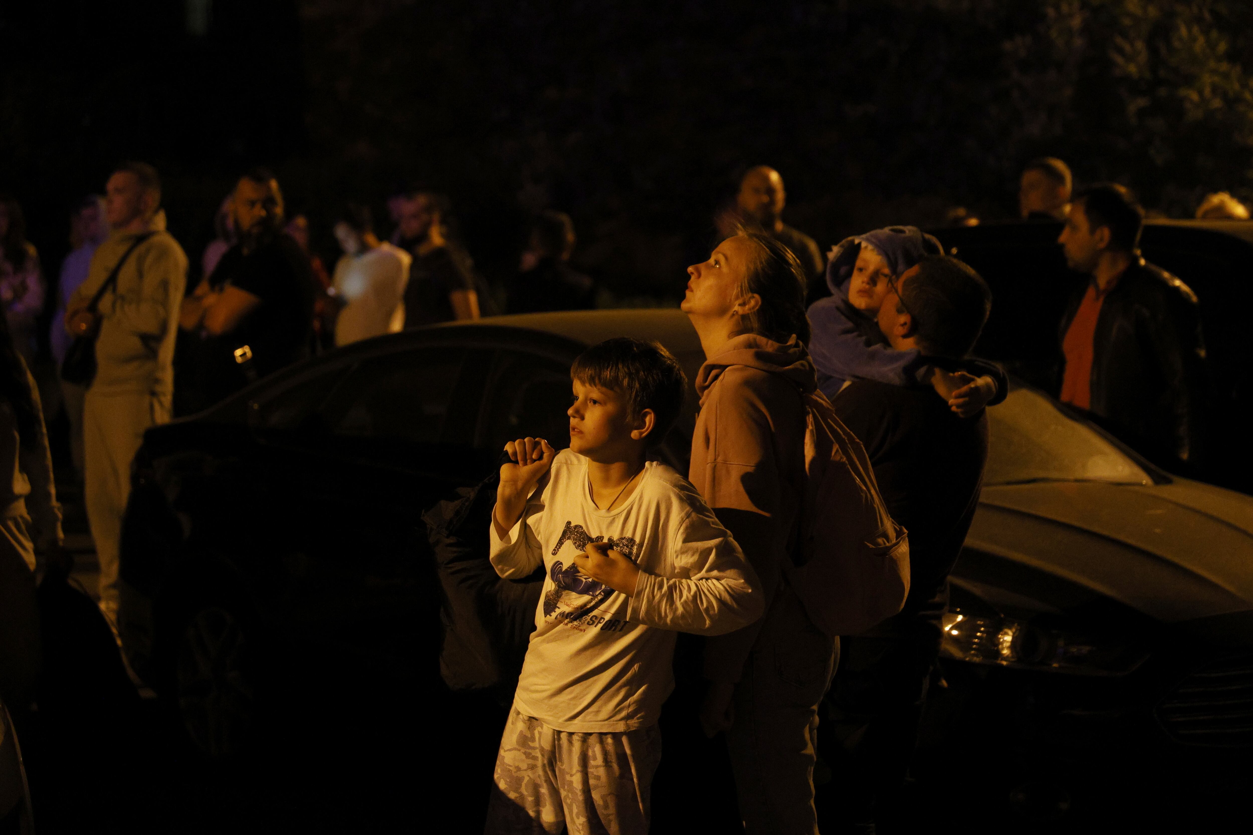 La gente mira un incendio en la parte superior de un edificio residencial luego de un ataque con drones, en Kiev, Ucrania, el sábado 20 de mayo de 2023.