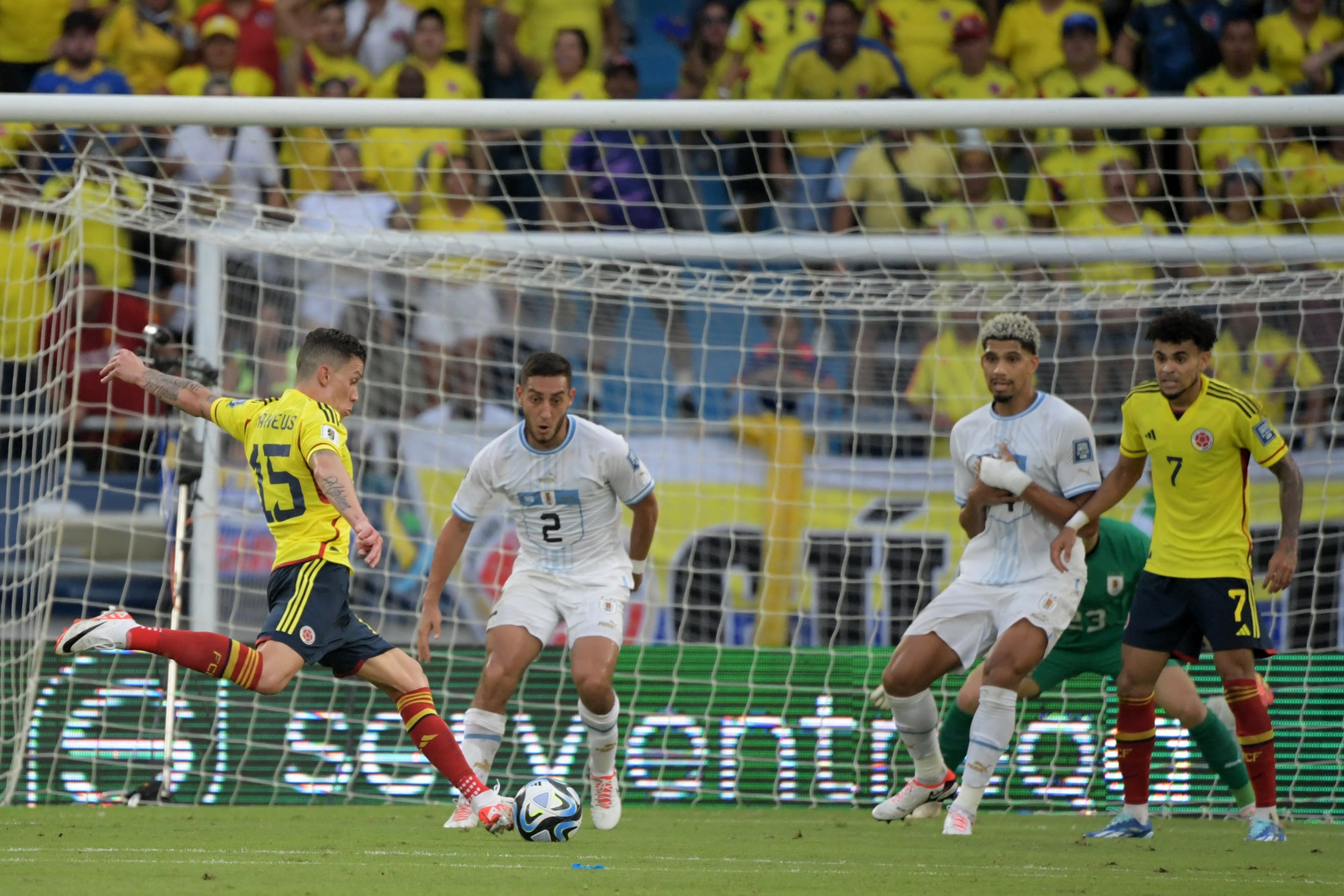 Colombia's midfielder Matheus Uribe (L) strikes the ball to score his team's second goal past Uruguay's defenders Sebastian Caceres (2-L), Ronald Araujo and goalkeeper Santiago Mele (covered) as Colombia's forward Luis Diaz looks on during the 2026 FIFA World Cup South American qualification football match between Colombia and Uruguay at the Roberto Melendez Metropolitan Stadium in Barranquilla, Colombia, on October 12, 2023. (Photo by Raul ARBOLEDA / AFP)