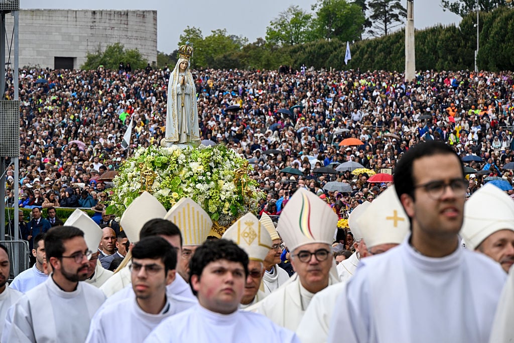 Obispos y sacerdotes caminan bajo la lluvia frente a la imagen de Nuestra Señora de Fátima, llevada por portadores durante la procesión y misa en el Santuario de Fátima, el día del aniversario de las apariciones de Nuestra Señora de Fátima, el 13 de mayo de 2025 en Fátima, Portugal (Foto de Horacio Villalobos#Corbis/Getty Images)