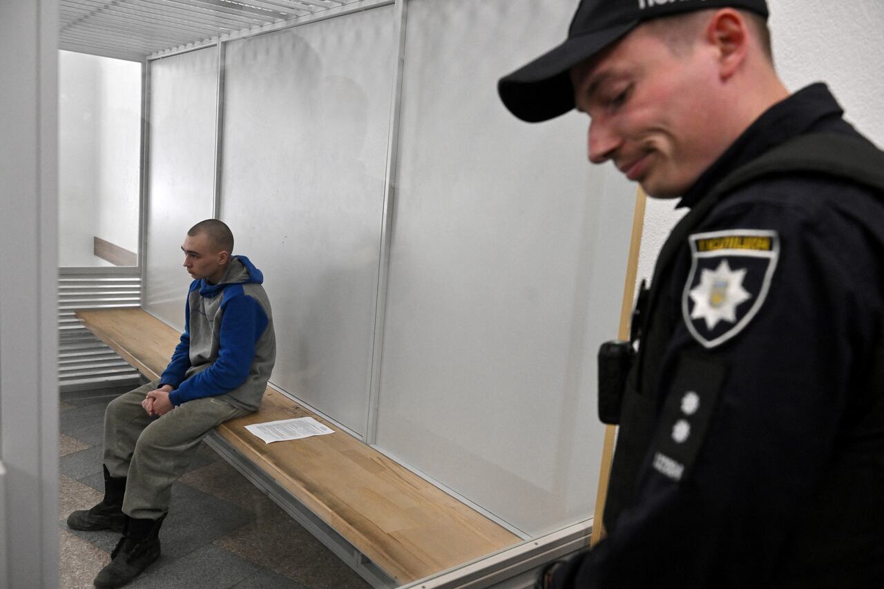 El soldado ruso Vadim Shishimarin se sienta en el banquillo del acusado en el segundo día de su juicio por cargos de crímenes de guerra por haber matado a un civil, en un tribunal de Kiev el 19 de mayo de 2022. - El primer soldado ruso enjuiciado por crímenes de guerra en Ucrania pidió "perdón" en un tribunal de Kiev el 19 de mayo y describió cómo mató a tiros a un civil en los primeros días de la invasión de Rusia. Los fiscales ucranianos solicitaron cadena perpetua. (Foto de Serguéi SUPINSKY / AFP)