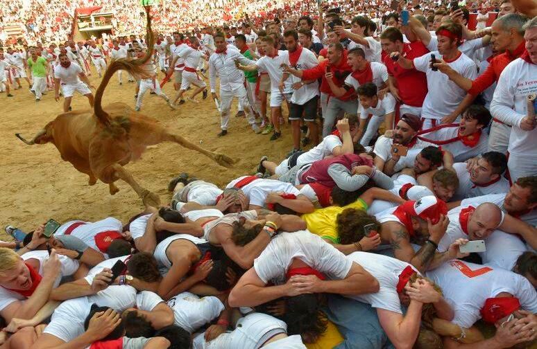 Una novilla salta sobre la gente en la plaza de toros durante el Festival de San Fermín en Pamplona, ??al norte de España, el 8 de julio de 2019. Cada día del festival se lanzan seis toros a las 8:00 a.m para correr por las calles estrechas y empedradas de la ciudad vieja sobre un curso de 850 metros. Por delante de ellos están los corredores, que intentan mantenerse cerca de los toros sin caerse ni ser corneados. (Foto de ANDER GILLENEA / AFP)