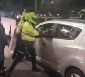 Policía rompiendo el vidrio de un carro en Bogotá