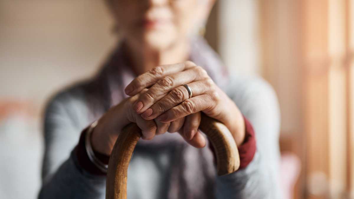 senior woman holding a cane in a retirement home