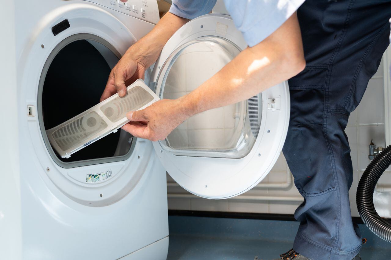 A Maintenance Engineer / Handyman is repairing a domestic Tumble Dryer, he is checking the filters first before dismantling the machine.