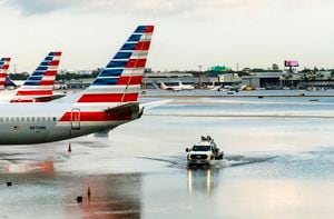 Los aviones de American Airlines se sientan en la terminal mientras un camión atraviesa la pista inundada en el Aeropuerto Internacional de Fort Lauderdale-Hollywood