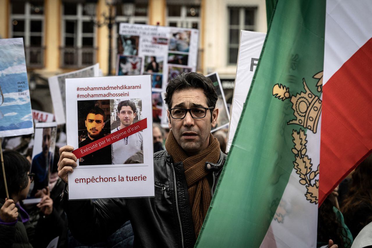 A protestor holds portraits of Iranian Mohammad Mehdi Karami (L) and  Mohammad Hosseini (2nd-L), protestors who were recently executed in Iran, during a rally in Lyon on January 8, 2023 against the Iranian regime, marking third anniversary of the downing of Ukrainian passenger jet, flight PS752 by Iranian forces shortly after it's takeoff from Tehran and to pay tribute to Mohammad Moradi, an Iranian student who committed suicide by drowning himself in the Rhone River in December 2022 to draw attention to the situation in Iran. (Photo by JEAN-PHILIPPE KSIAZEK / AFP)