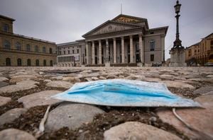 A blue mouth-nose protector lies on the pavement in front of the Bavarian State Opera in the centre of the city of Munich, Germany, during the lockdown on Tuesday, Jan. 5, 2020. (Peter Kneffel/dpa via AP)