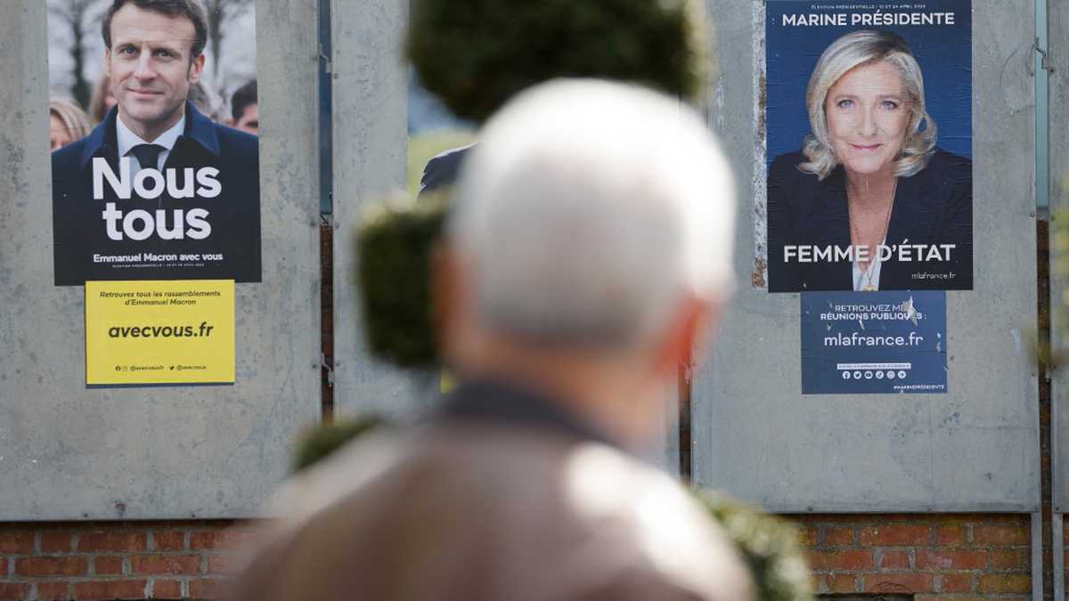 Un hombre camina junto a carteles de campaña de los candidatos presidenciales franceses, el actual presidente Emmanuel Macron (L) y la candidata presidencial del partido de extrema derecha francés Rassemblement National (RN) Marine Le Pen en Denain, el 11 de abril de 2022. Emmanuel Macron obtuvo el 27,85 por ciento de los votos. en la primera ronda de las elecciones presidenciales de Francia, mientras que la veterana de extrema derecha Marine Le Pen obtuvo un 23,15 por ciento, según los resultados finales del Ministerio del Interior el lunes.(Foto por Ludovic MARIN / AFP)