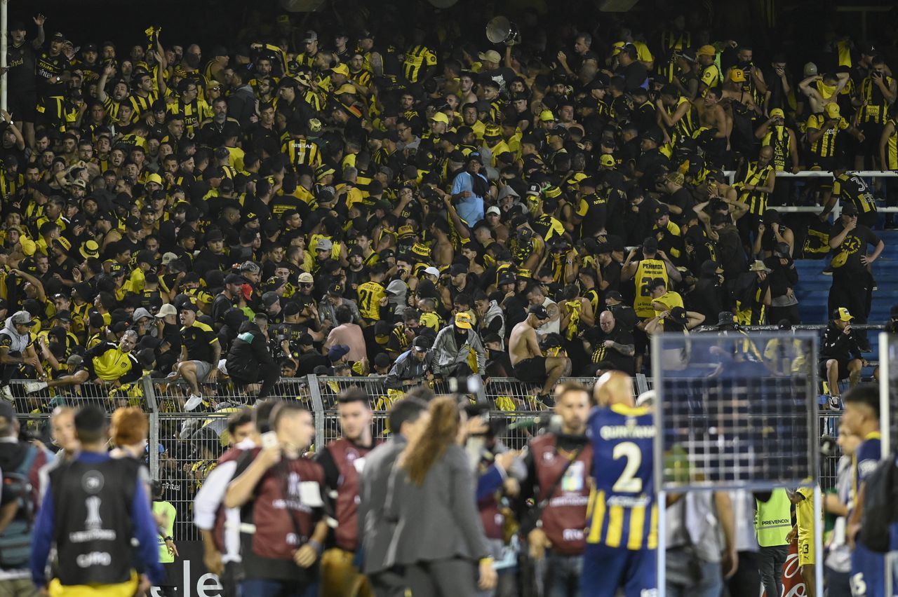 Fans of Pe�arol clash with the police on the stands during the Copa Libertadores group stage first leg football match between Argentina's Rosario Central and Uruguay's Pe�arol at the Gigante de Arroyito Stadium in Rosario, Argentina, on April 4, 2024. (Photo by Marcelo Manera / AFP)