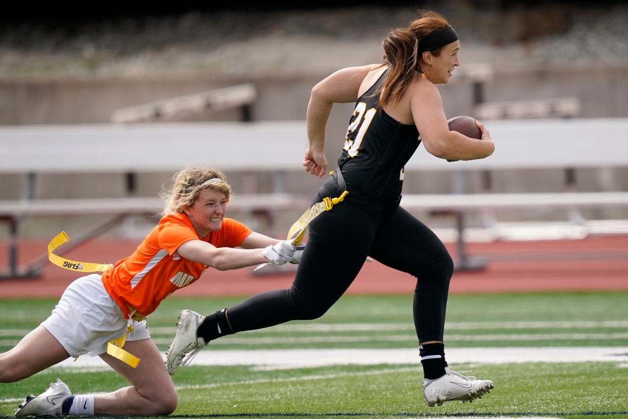 FILE - Ottawa quarterback Madysen Carrera (21) is tackled by Midland defender Casey Thompson, left, during an NAIA flag football game in Ottawa, Kan., March 26, 2021. Flag football took a key step toward becoming an Olympic sport in 2028, a victory for the NFL and organizers in Los Angeles who will bring a distinctly American sport to the Summer Games as they return to the United States for the first time in 32 years. (AP Photo/Orlin Wagner, File)