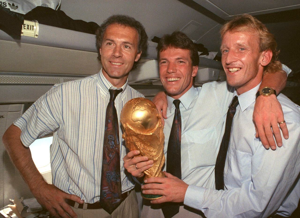 From left, Germany national soccer team's Franz Beckenbauer, Lothar Matthaeus and Andreas Brehme pose with the World Cup trophy on July 9, 1990. Andreas Brehme, who scored the only goal as West Germany beat Argentina to win the 1990 World Cup final, has died. He was 63. Brehme’s partner Susanne Schaefer has confirmed his death in a statement to Germany’s dpa news agency. (Wolfgang Eilmes/dpa via AP)