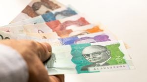 Dinero colombiano, pesos de papel, sostenido en la mano contra un fondo brillante billetes