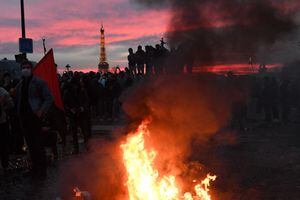 Los manifestantes se paran alrededor de las barreras en llamas durante una manifestación en la Place de la Concorde.