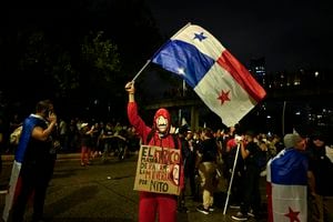 Un manifestante con una máscara y un traje de Money Heist ondea una bandera panameña durante una marcha contra el contrato gubernamental con la compañía minera canadiense First Quantum y su filial Minera Panamá en la ciudad de Panamá el 27 de octubre de 2023. (Foto de LUIS ACOSTA/AFP)