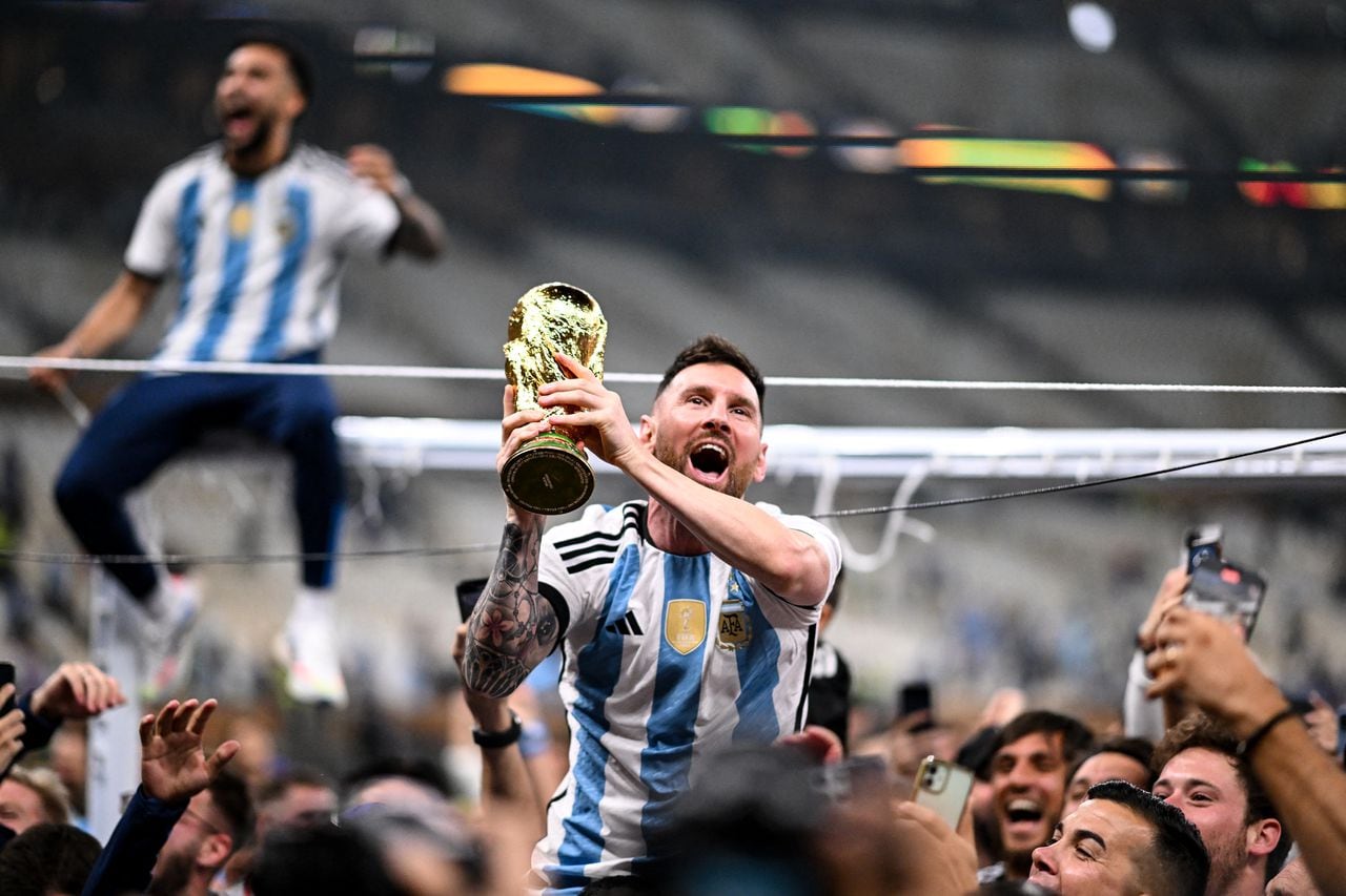 Argentina's forward #10 Lionel Messi lifts the FIFA World Cup Trophy as he celebrates with supporters winning the Qatar 2022 World Cup final football match between Argentina and France at Lusail Stadium in Lusail, north of Doha on December 18, 2022. (Photo by Kirill KUDRYAVTSEV / AFP)