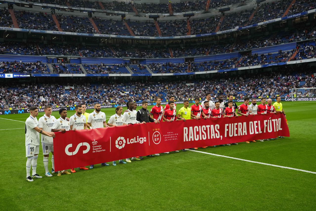 Players lift a banner reading 'Racists out of football' prior to a Spanish La Liga soccer match between Real Madrid and Rayo Vallecano at the Santiago Bernabeu stadium in Madrid, Spain, Wednesday, May 24, 2023. (AP Photo/Manu Fernandez)