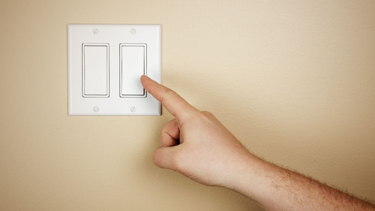 Una mano masculina se mueve para apagar un interruptor de luz.